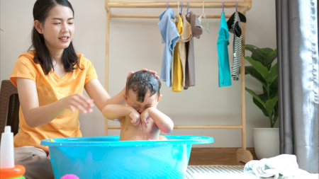 Mom and little child with taking a shower and dressing at home in the morningの写真素材
