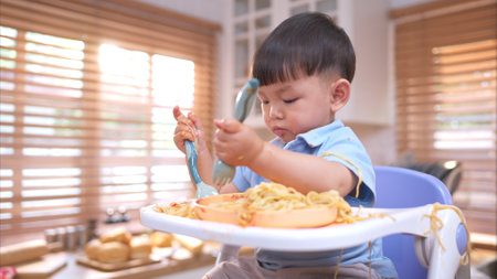 Happy Asian boy enjoying mealtime in the kitchenの写真素材