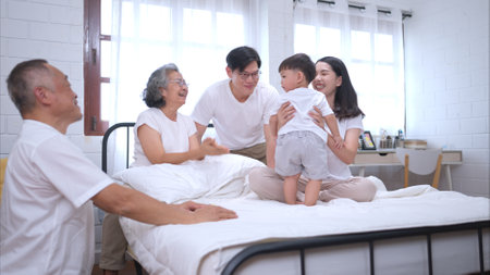 Before putting the kids to bed, parents, grandparents, and kid unwind and play in the bedroomの写真素材