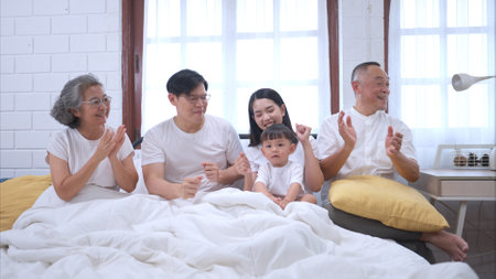 Before putting the kids to bed, parents, grandparents, and kid unwind and play in the bedroomの写真素材