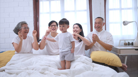 Before putting the kids to bed, parents, grandparents, and kid unwind and play in the bedroomの写真素材
