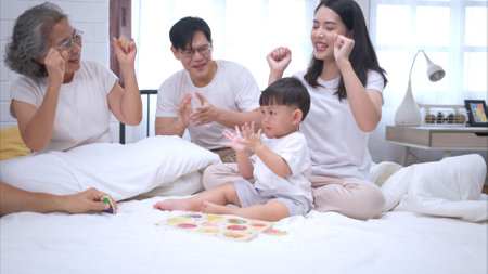 Before putting the kids to bed, parents, grandparents, and kid unwind and play in the bedroomの写真素材