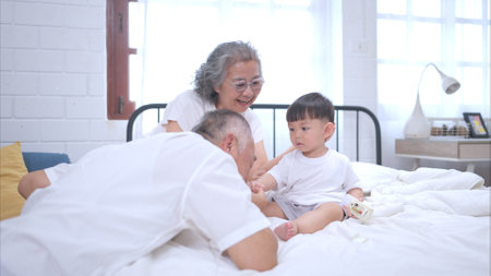 Before putting the kids to bed, grandparents, and kid unwind and play in the bedroomの写真素材