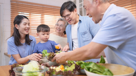 Happy Asian family preparing food together in a bright kitchen, sharing joyful moments with a toddler during a fun and healthy cooking timeの写真素材