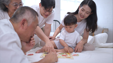 Before putting the kids to bed, parents, grandparents, and kid unwind and play in the bedroomの写真素材