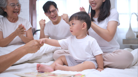 Before putting the kids to bed, parents, grandparents, and kid unwind and play in the bedroomの写真素材