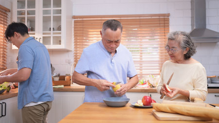 Happy Asian family preparing food together in a bright kitchen, sharing joyful moments with a toddler during a fun and healthy cooking timeの写真素材