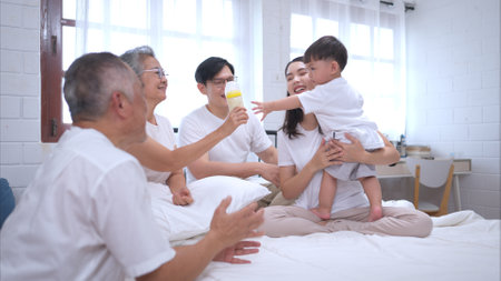 Before putting the kids to bed, parents, grandparents, and kid unwind and play in the bedroomの写真素材