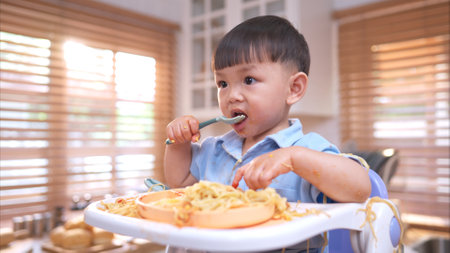 Happy Asian boy enjoying mealtime in the kitchenの写真素材