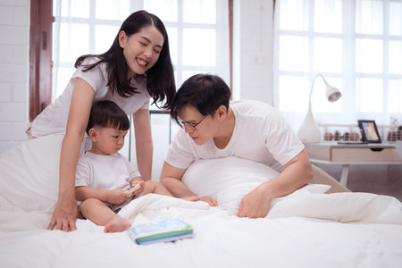 Before putting the kids to bed, parents, and kid unwind and play in the bedroomの写真素材