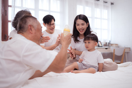 Before putting the kids to bed, parents, grandparents, and kid unwind and play in the bedroomの写真素材