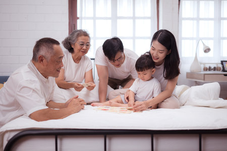 Before putting the kids to bed, parents, grandparents, and kid unwind and play in the bedroomの写真素材