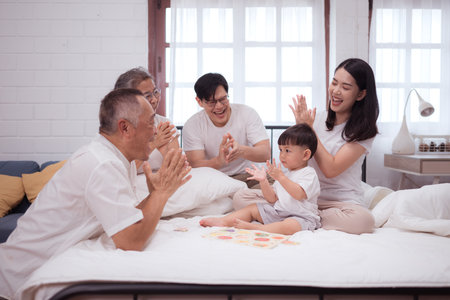 Before putting the kids to bed, parents, grandparents, and kid unwind and play in the bedroomの写真素材