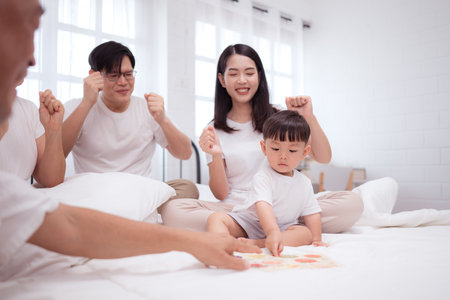 Before putting the kids to bed, parents, grandparents, and kid unwind and play in the bedroomの写真素材