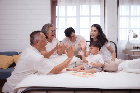 Before putting the kids to bed, parents, grandparents, and kid unwind and play in the bedroomの写真素材