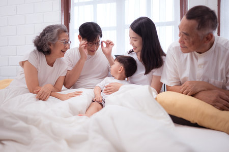 Before putting the kids to bed, parents, grandparents, and kid unwind and play in the bedroomの写真素材