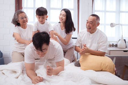 Before putting the kids to bed, parents, grandparents, and kid unwind and play in the bedroomの写真素材