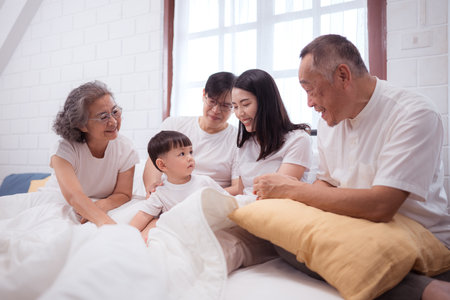 Before putting the kids to bed, parents, grandparents, and kid unwind and play in the bedroomの写真素材