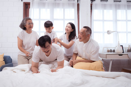 Before putting the kids to bed, parents, grandparents, and kid unwind and play in the bedroomの写真素材