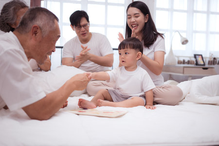 Before putting the kids to bed, parents, grandparents, and kid unwind and play in the bedroomの写真素材