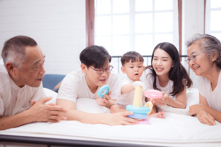 Before putting the kids to bed, parents, grandparents, and kid unwind and play in the bedroomの写真素材