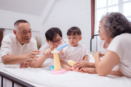 Before putting the kids to bed, parents, grandparents, and kid unwind and play in the bedroomの写真素材