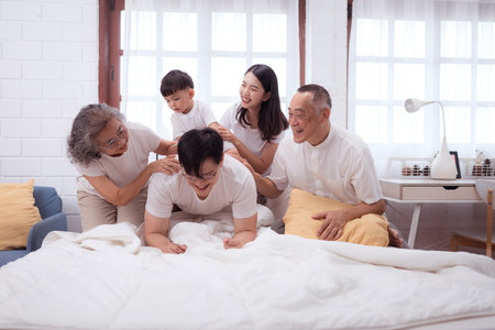 Before putting the kids to bed, parents, grandparents, and kid unwind and play in the bedroomの写真素材