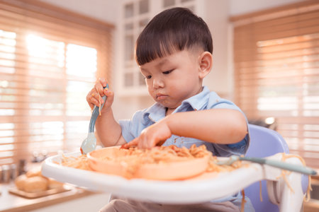 Happy Asian boy enjoying mealtime in the kitchenの写真素材