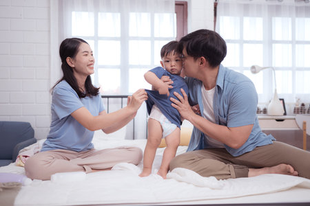 Happy time after bath, Asian kid and parents enjoying are having fun applying cream, powder and dressing upの写真素材