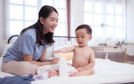 Happy time after bath, Asian kid and mother enjoying are having fun applying cream, powder and dressing upの写真素材