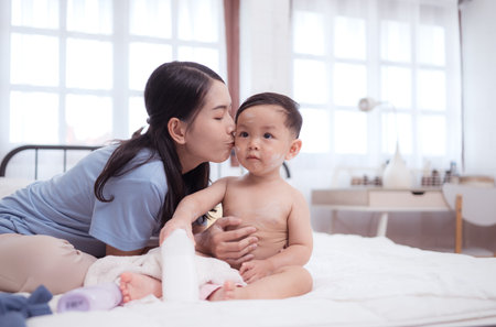 Happy time after bath, Asian kid and mother enjoying are having fun applying cream, powder and...