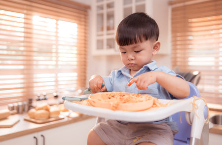 Happy Asian boy enjoying mealtime in the kitchenの写真素材