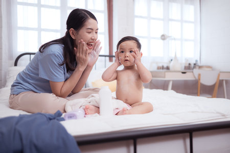 Happy time after bath, Asian kid and mother enjoying are having fun applying cream, powder and dressing upの写真素材