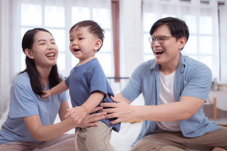 Happy time after bath, Asian kid and parents enjoying are having fun applying cream, powder and dressing upの写真素材