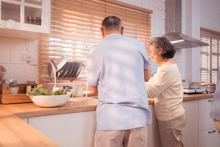 Happy Asian grandparents enjoying cooking the mealtime in the kitchenの写真素材