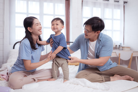 Happy time after bath, Asian kid and parents enjoying are having fun applying cream, powder and dressing upの写真素材
