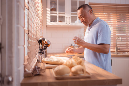 Happy Asian grandfather enjoying cooking the mealtime in the kitchenの写真素材