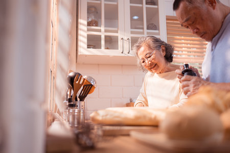 Happy Asian grandparents enjoying cooking the mealtime in the kitchenの写真素材