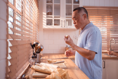 Happy Asian grandfather enjoying cooking the mealtime in the kitchenの写真素材