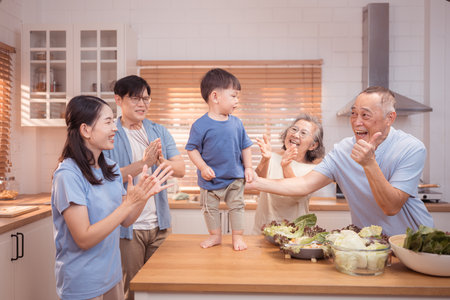 Happy Asian family preparing food together in a bright kitchen, sharing joyful moments with a toddler during a fun and healthy cooking timeの写真素材