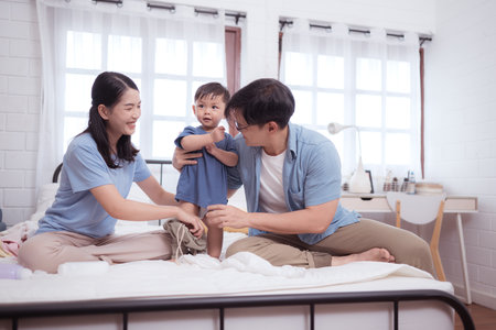 Happy time after bath, Asian kid and parents enjoying are having fun applying cream, powder and dressing upの写真素材
