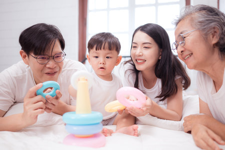Before putting the kids to bed, parents, grandparents, and kid unwind and play in the bedroomの写真素材