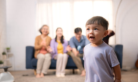 Happy multi-generational Asian family enjoying quality time together at home, cheering and smiling with a toddlerの写真素材