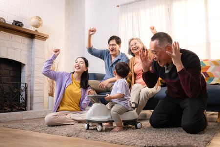 Happy multi-generational Asian family enjoying quality time together at home, cheering and smiling...