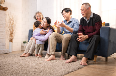 Happy multi-generational Asian family enjoying quality time together at home, cheering and smiling with a toddlerの写真素材