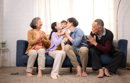 Happy multi-generational Asian family enjoying quality time together at home, cheering and smiling...
