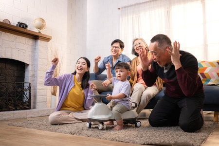 Happy multi-generational Asian family enjoying quality time together at home, cheering and smiling...