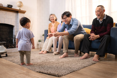Happy multi-generational Asian family enjoying quality time together at home, cheering and smiling with a toddlerの写真素材