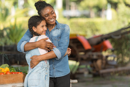 Smiling mom and daughter with a tray of fruit and vegetable, enjoying a day of learning and gardening outdoorsの写真素材
