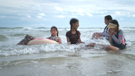 Happy children playing together in the sea, enjoying a fun summer day at the beach with laughter and...